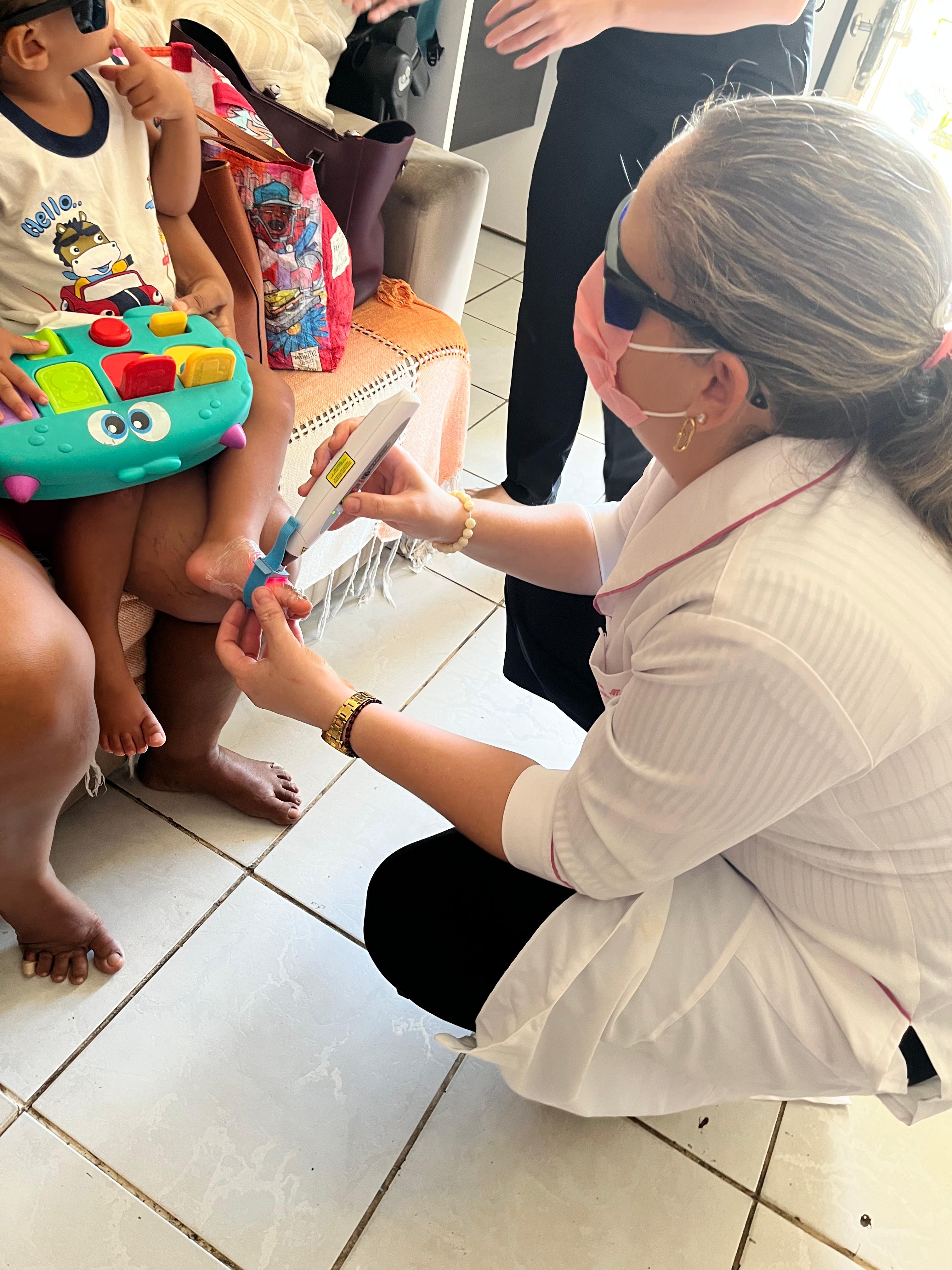 Patrícia Mendonça aplicando laserterapia pediátrica no pé de uma criança